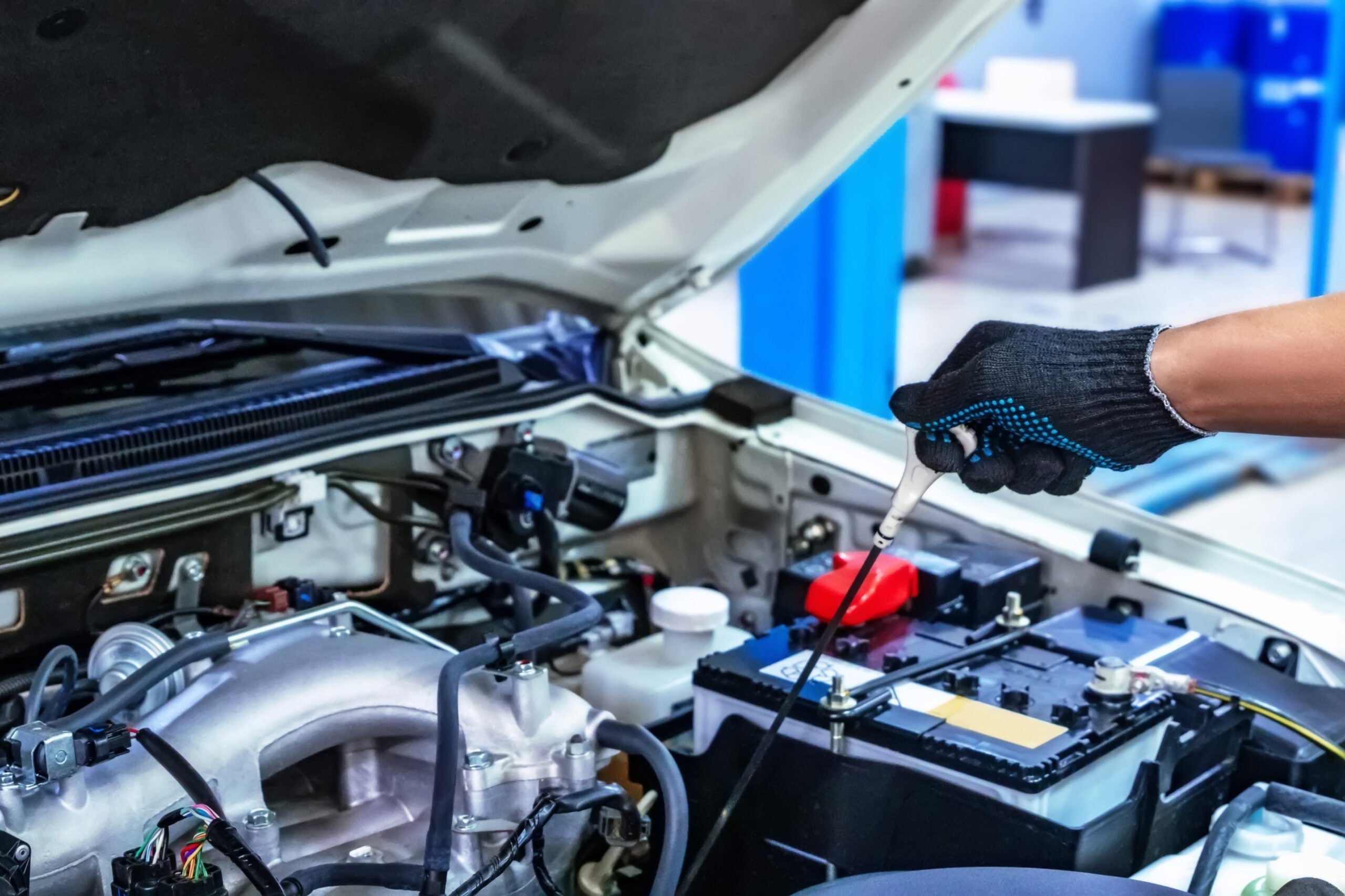 Auto mechanic working with open car hood in garage. Car repair service. Auto mechanic works with car hood open in car repair shop. Official car service concept